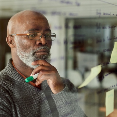Older man thinking at a whiteboard